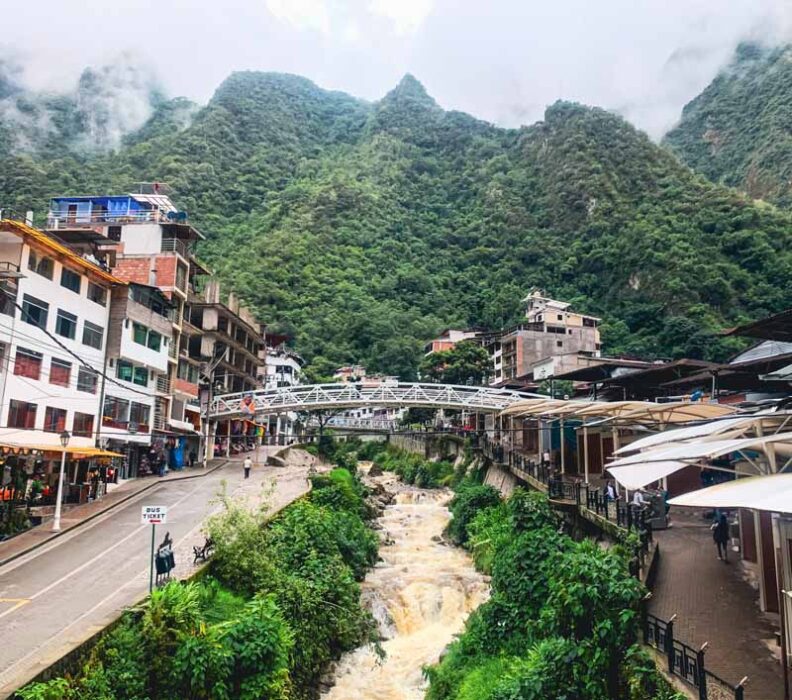 Aguas calientes village stradles the river with the misty mountains in the backdrop