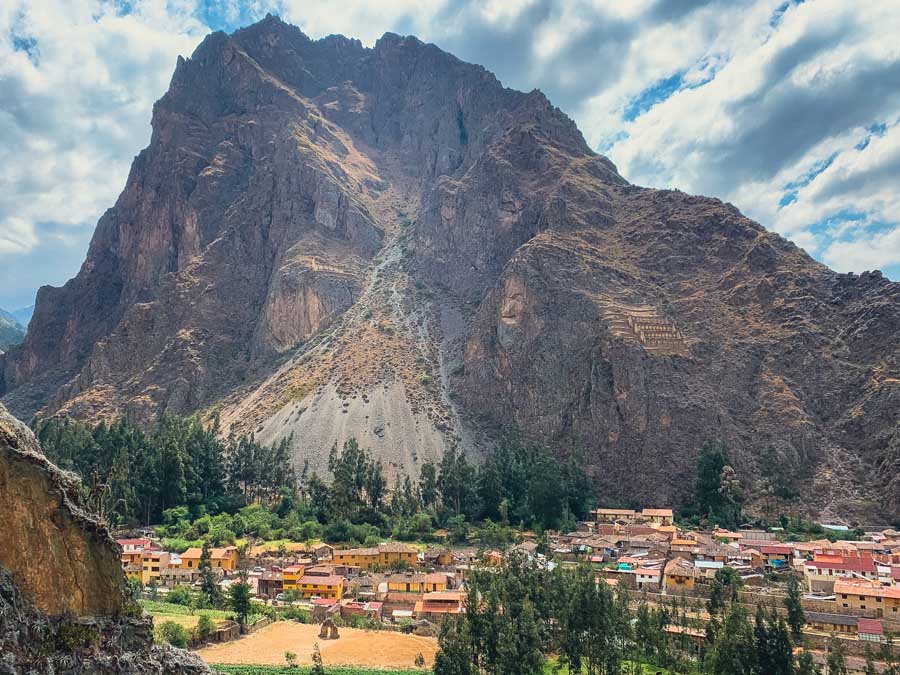 Wiracocha Face in Mountain, Inca Gods in Mountain, Ollantaytambo, Sacred Valley, Inca sites in the Sacred Valley, Inca ruins, Ollantaytambo Archaeological Park, Ollantaytambo village, houses, sky, clouds, natural landmarks in Peru