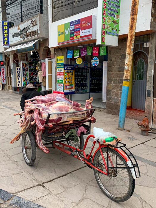 Chivay village Peru, man with cart, buildings, things to do in Yanque Peru, meat on bicycle