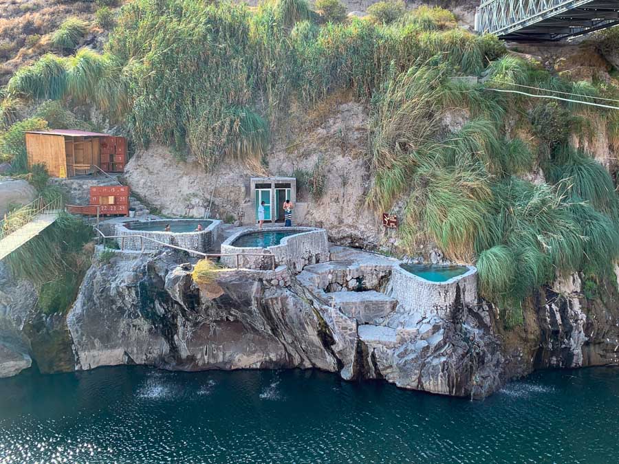 Baños termales de Chacapi, Chacapi hot springs, Peru hot springs, Colca Canyon, things to do in Yanque Peru, Yanque hot springs, Colca Canyon Peru hot springs, pools, changing room, Colca River, Colca Canyon Peru hot springs, people, plants, bridge, best hot springs in Peru