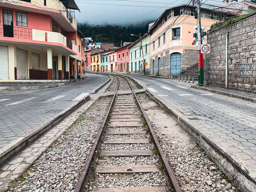 colorful buildings, places to visit in ecuador, ecuador villages, train tracks, street, mountains, clouds, trees, things to do in alausi ecuador