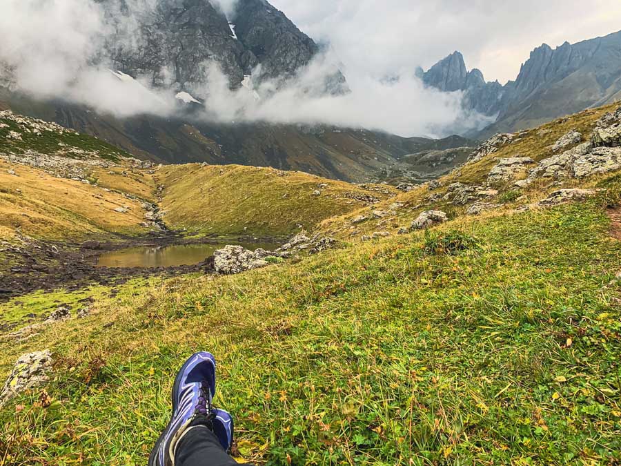 Green Abudelauri Lakes, Juta to Roshka trek, trail runners, rocks, grass, caucasus mountains, clouds, kazbegi treks