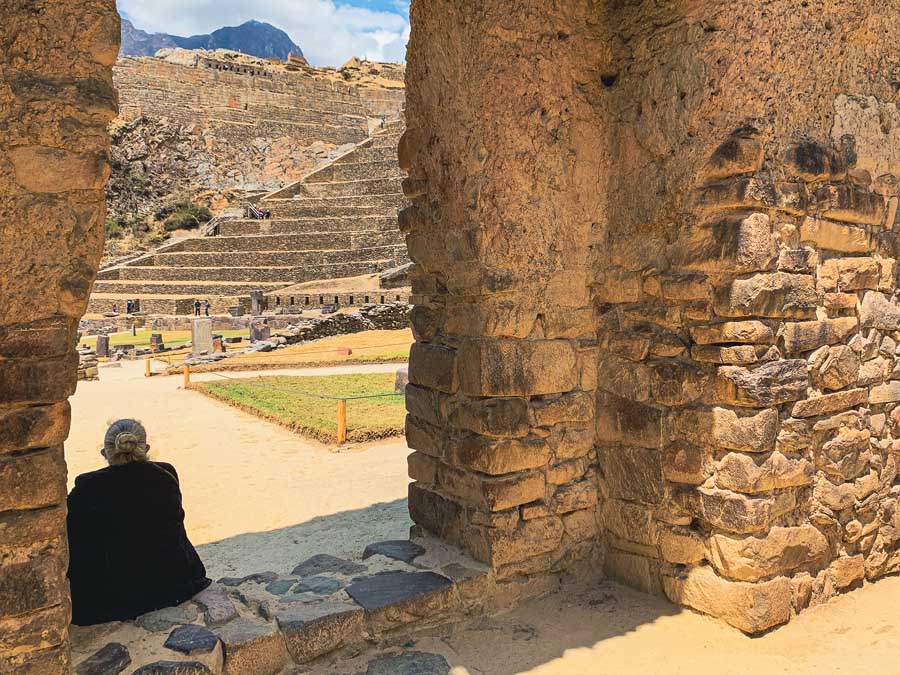 Ollantaytambo Sanctuary, Ollantaytambo ruins, things to do in ollantaytambo peru, woman, terraces, mountains, sky, clouds