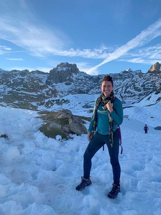 woman surrounded by mountains with snow in the Picos de Europa National Park
