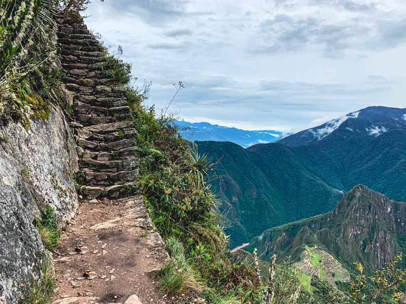 stone steps lead to Machu Picchu Mountain summit with the Inca ruins below