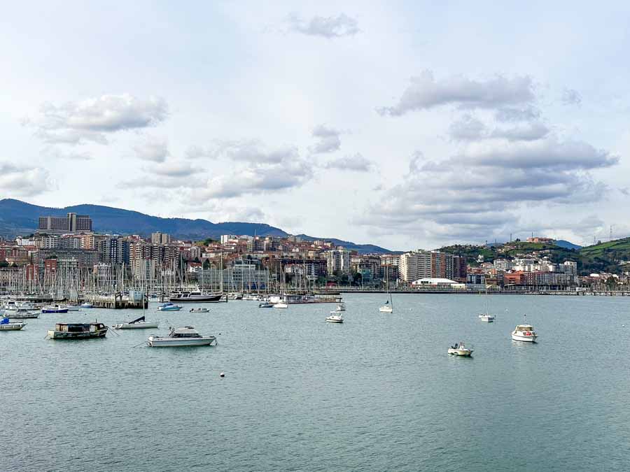 small boats sit at the Las Arenas marina with the city and mountains in the backdrop